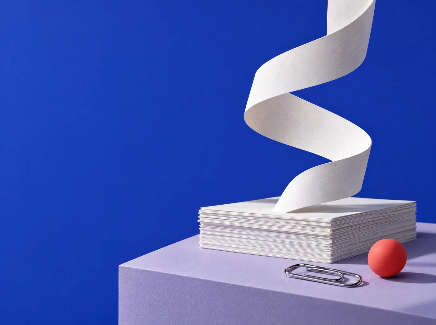 A sculptural white paper ribbon rising above a stack of documents against cobalt blue